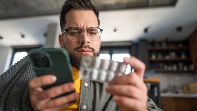 
		Kranker Mann mit Handy und Tabletten in der Hand
	